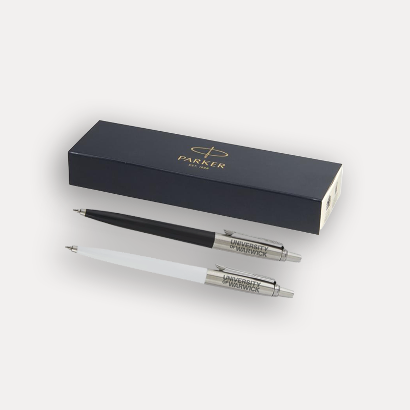 A Parker ballpoint pen set with two pens, one black and one white, displayed in front of their presentation box on a light grey background