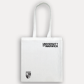 A white canvas tote bag with black printed text reading 'UNIVERSITY OF WARWICK' and a small black crest logo near the bottom left, shown against a light grey background.